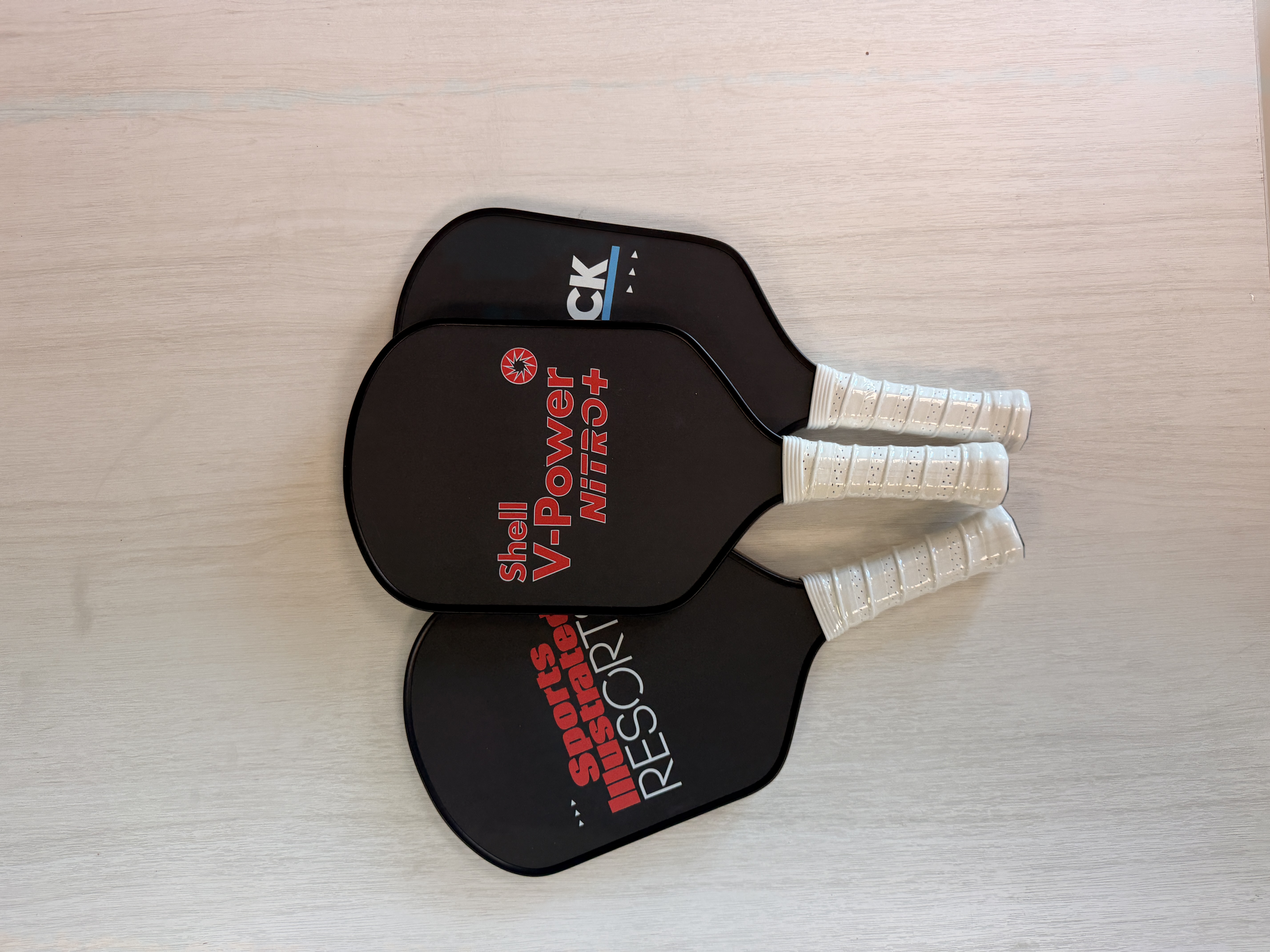 A pickleball paddle and ball resting on a blue court surface with a net in focus.