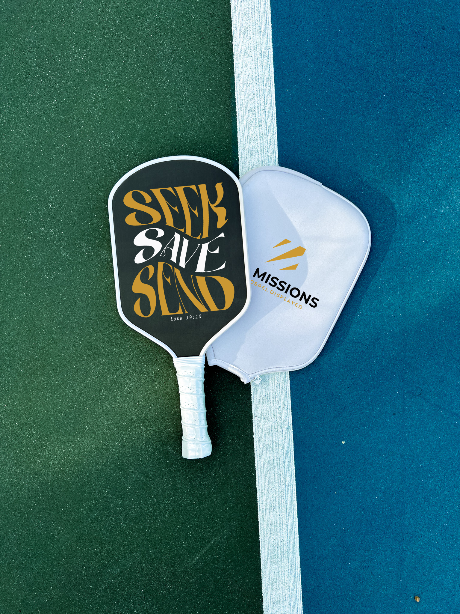 Close-up of a pickleball paddle and ball on a vibrant blue court surface showing geometric lines.